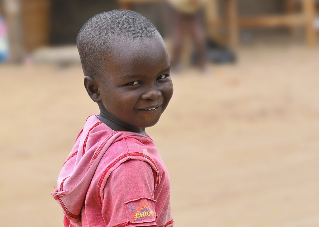Un pequeño niño africano sonríe a la cámara. Su sonrisa es cautivadora, cariñosa, contagiosa.